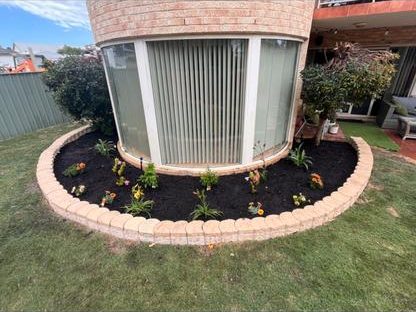 New curved garden bed with brick edging